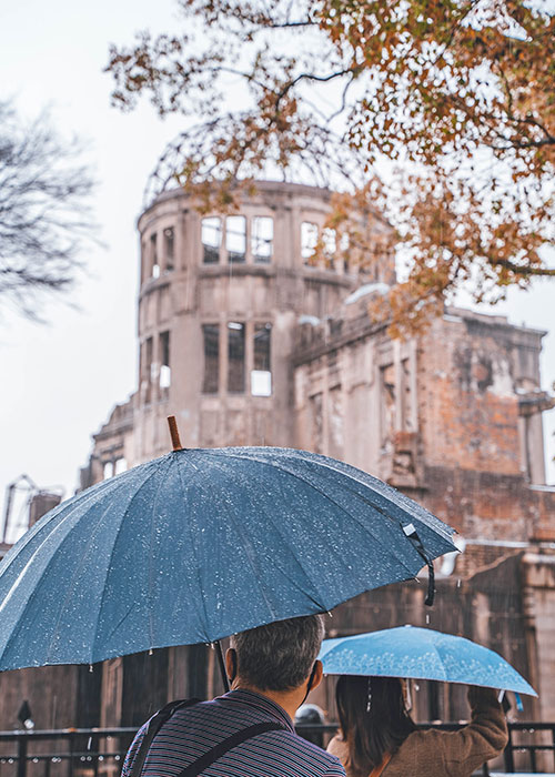 A visitors looks up at the Hiroshima Peace Memorial in the rain